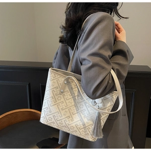 Dettaglio della borsa tote in jacquard grigio chiaro con motivi floreali e nappa sulla modella