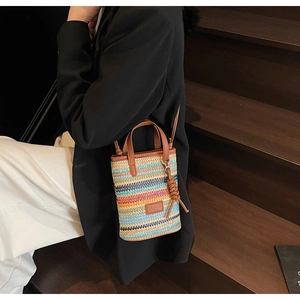 Detail view of colorful striped straw woven mini bag with leather handles and long shoulder strap