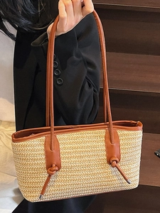 Bohemian straw tote bag with brown leather knotted handles on a stylish model