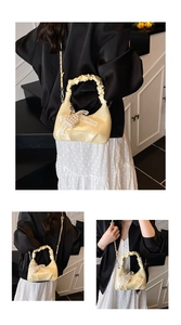 Detail of cream pleated cloud bag featuring fashion embossing and a pearl heart charm