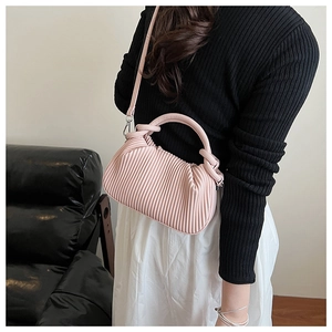 Detail of a pink pleated cloud bag with a cylindrical handle and crossbody strap style