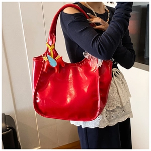 Detail of red wax leather tote bag featuring a cute pony charm and white lace trim
