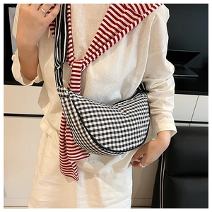 Detailed view of checkered crescent crossbody bag worn by a model in casual white outfit