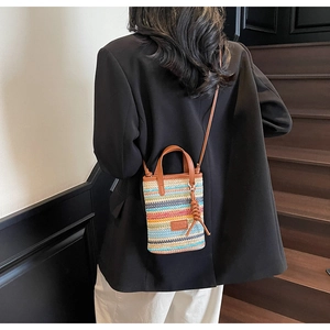 Detail view of colorful striped woven crossbody bag with leather handle and strap