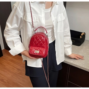Detail of red quilted patent leather mini backpack with chain strap and twist lock