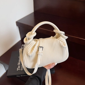 Close-up of cream white pleated handbag with unique knotted handle and silver metal hardware