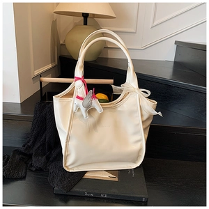 Detailed view of white oil wax tote bag with Pegasus charm and organza ribbon bow