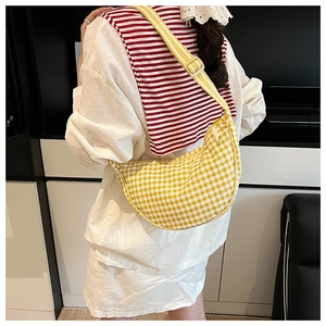 Detailed back view of a yellow checkered crescent crossbody bag worn by a model