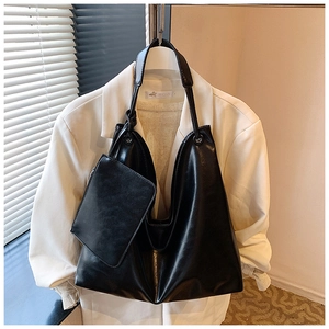 Detail of black faux leather tote set with matching pouch hanging on a white blazer