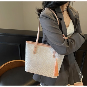 Dettaglio della borsa tote ricamata bianca con manici rosa e ciondolo con nappine