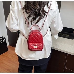 Detail of red quilted patent leather mini backpack with silver chain strap on model