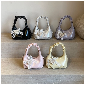 Detailed view of pleated dumpling bags in five colors with pearl heart charms and bows