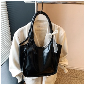 Detail view of black oil-wax leather tote bag with lace bow and leather pegasus charm