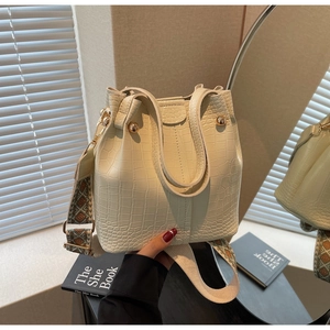 Detail view of cream bucket bag showing crocodile texture and ethnic embroidery strap