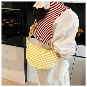 Detail of yellow and white checkered canvas crescent bag with adjustable striped strap