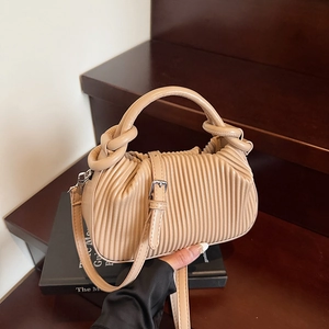 Detail of beige pleated handbag with knotted handle and elegant decorative strap buckle