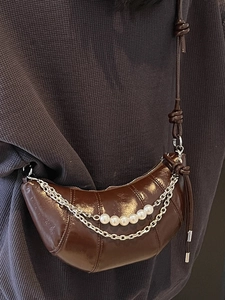 Brown patent leather croissant bag with silver chains and pearls on a model
