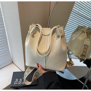 Detail of creamy white bucket bag with crocodile texture and ethnic pattern strap
