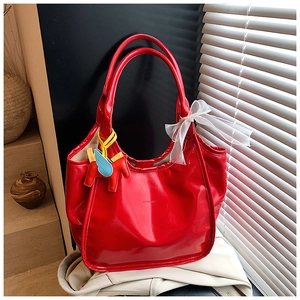 Macro detail of red oil wax tote bag featuring lace bow and horse charm accessory