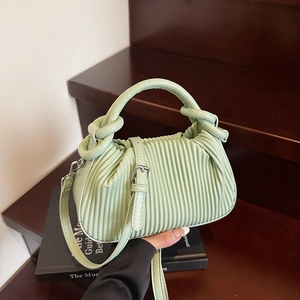 Detailed close-up of light green pleated handbag with round handle and leather strap buckle