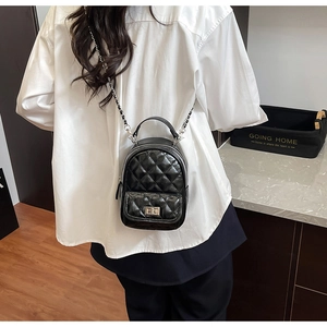 Detail of a mini black quilted backpack with silver chain straps and metallic turn-lock