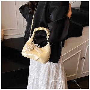 Detail of cream pleated handbag with pearl heart charm and lace bow decoration