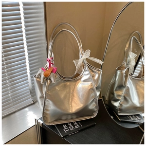 Detailed macro view of silver metallic tote bag featuring horse charm and bow detail
