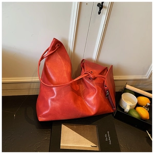 Detail of red oversized tote bag featuring soft faux leather texture and slender handles