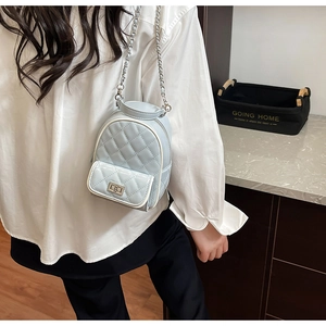 Detailed view of light blue quilted mini backpack with silver metal chain on model