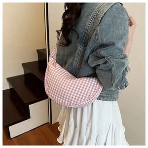 Detail view of the pink and white checkered crescent crossbody bag on a model