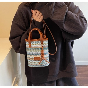 Detail showing the colorful wave-pattern knit texture and brown leather handles of the bag