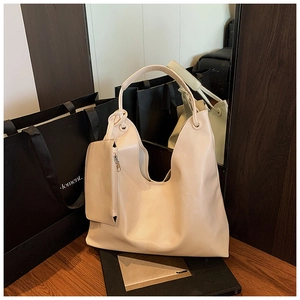 Detail view of large cream tote bag with U-shaped opening and matching zipper pouch charm