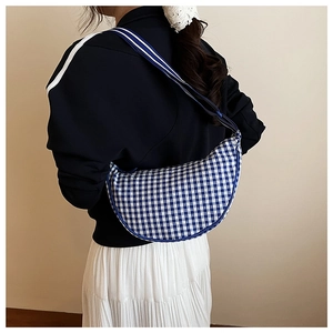 Detailed view of a blue and white gingham crescent shoulder bag with striped woven strap