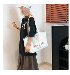 Détail du sac cabas en toile blanche avec broderie de texte rouge et grande capacité