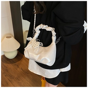 Detail of white hobo bag showing pleated handle, pearl heart charm and lace bow