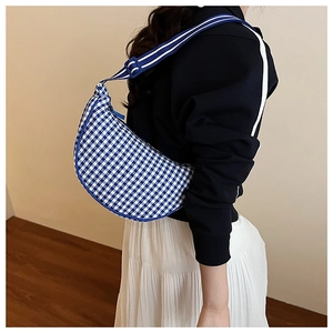 Detail view of the blue and white checkerboard crescent bag worn over the shoulder