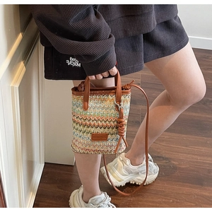 Detail shot of multi-color woven bucket bag with leather strap and stripe patterns