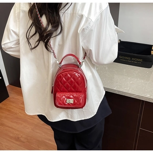 Detail of red quilted patent leather mini backpack with silver chain strap on a model