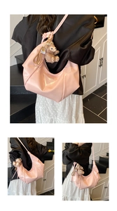 Detail view of pink glossy hobo bag featuring natural pleats and a plush bear pendant
