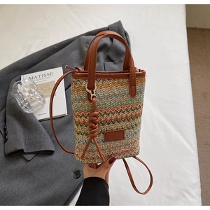 Detail of colorful woven bucket bag with wave pattern and brown leather straps