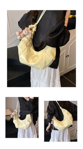 Close-up of bright yellow shiny leather hobo bag with a cute plush bear charm detail