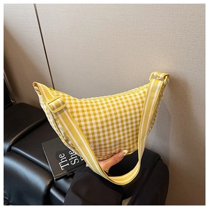 Detail of yellow checkered crescent bag showing woven texture and adjustable strap