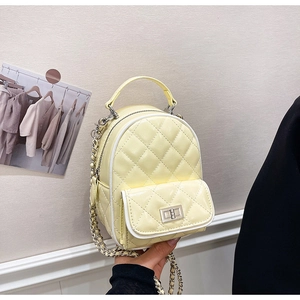 Close-up of quilted pale yellow faux leather mini backpack with silver chain strap and twist lock