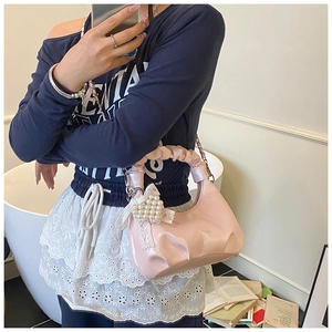 Detail of pink glossy pleated cloud bag with pearl heart charm accessory on handle