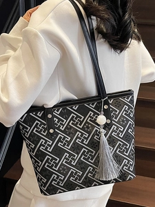 Borsa tote nera con motivi geometrici bianchi e nappa mostrata sulla spalla della modella