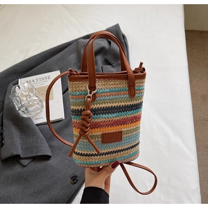Close-up of colorful striped woven crossbody bag with brown leather strap and handle