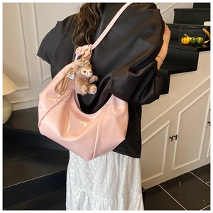 Close-up of pink patent leather hobo bag with glossy finish and cute plush bear charm