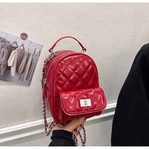 Detail of red quilted mini backpack with glossy finish and silver chain straps
