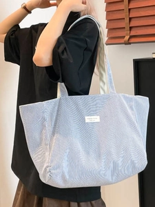 Grand sac cabas en toile à rayures bleues et blanches porté par un mannequin en studio