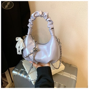 Detail of lavender dumpling bag with pleated handle, silver chain and lace bow ornament
